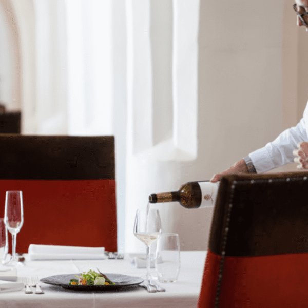 waiter pouring a glass of wine at divinus restaurante in evora 